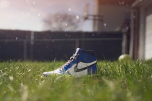 A blue Nike sneaker sits in vibrant green grass, capturing a sunny outdoor scene.